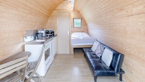 A compact, wooden-paneled room with a kitchenette, a bed, and a seating area. - 1 bedroom accommodation in Ross-on-Wye (Ross-on-Wye)