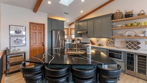 A modern kitchen with a central island, bar stools, grey cabinets, and a skylight. - The Raven (Banner Elk)