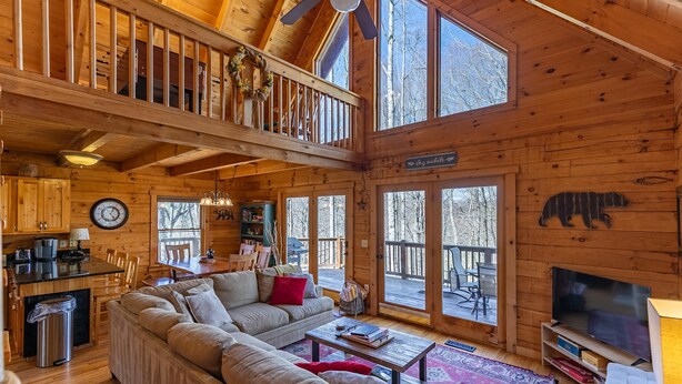A spacious wooden cabin with a large living area, a dining table, and a TV. - Mimi's Cottage (Blowing Rock)