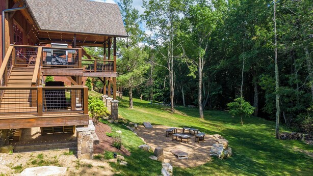 A multi-level wooden cabin with outdoor seating and a stone pathway. - The Sheltered Elk at Eagles Nest (Banner Elk)