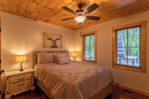 A bedroom with a bed, nightstands, a ceiling fan, and two windows. - Laurel Creek Lodge (Banner Elk)