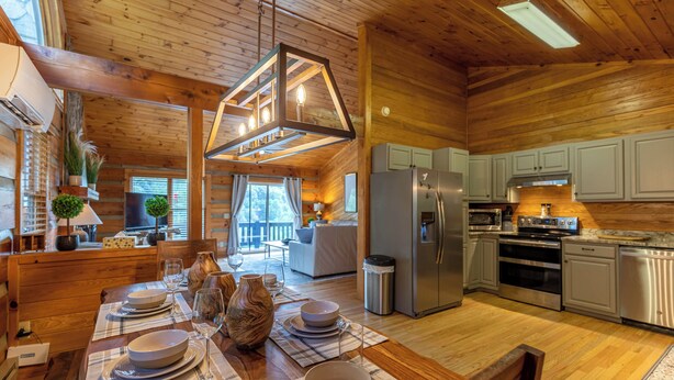 A cozy cabin with a wooden interior, a dining area set for four, and a kitchen with modern appliances. - Horse Valley Lodge (Boone)