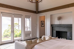A bedroom with a large bed, a fireplace, and a view through a sliding door. - The Outside Inn at Eagles Nest (Banner Elk)