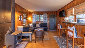 A cozy cabin interior with a sofa, chairs, a table, a fireplace, and a kitchen area. - Boone Folly (Boone)