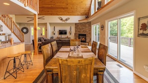 A spacious living area with a wooden dining table, high ceilings, and a fireplace. - 4 Bears Lodge (Banner Elk)