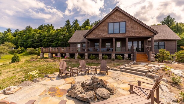 A large wooden house with a stone patio, outdoor seating, and a fire pit. - Sweet Serenity at Sweetgrass (Blowing Rock)