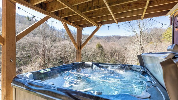 Un bain à remous installé sous une structure en bois, offrant une vue sur un paysage boisé.