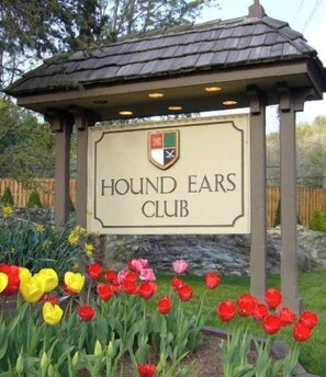 A sign for the Hound Ears Club with a logo, surrounded by a garden with tulips. - Peace of Mind at Hound Ears (Boone)