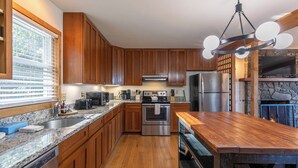 A modern kitchen with wooden cabinets, granite countertops, stainless steel appliances, and a central island. - Parkway Hideout (Boone)