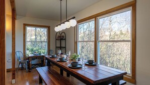 A dining area with a long wooden table, benches, and a hanging light fixture. - Parkway Hideout (Boone)