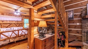 A cozy log cabin room with a bed, a dresser, and a lamp. - Whispering Pines (Fleetwood)