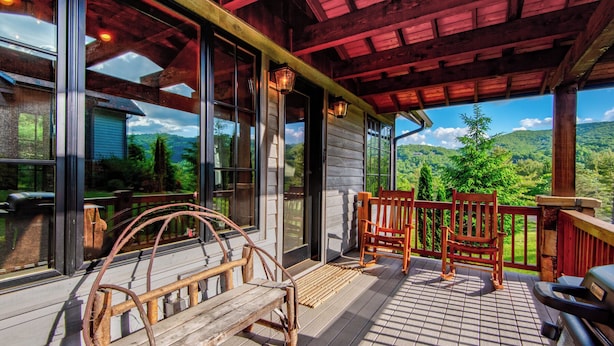 A wooden deck with a bench and chairs, large windows offering a view of a forested landscape. - Banner View (Banner Elk)