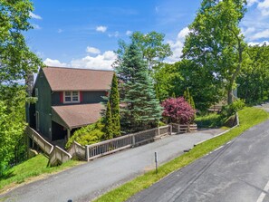 A two-story house with a red roof, a front porch, and a wooden fence. - Antlers Lodge (Blowing Rock)