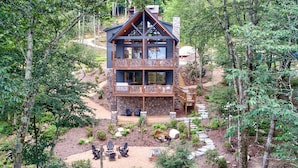 Eine zweistöckige Holzhütte mit Balkon, eingebettet in eine bewaldete Landschaft.