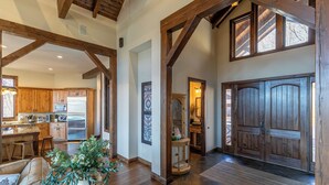 Un intérieur spacieux avec des poutres apparentes, une cuisine équipée d’appareils modernes et une grande porte en bois.