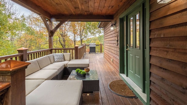 A wooden deck with a sofa and a table, a green door, and a view of trees. - A Change of Scenery at Yonahlossee (Boone)