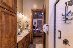 Ein Badezimmer mit Holzausstattung, einem Spiegel, einem Handtuchhalter und einer Dusche mit einem an der Tür hängenden Handtuch.