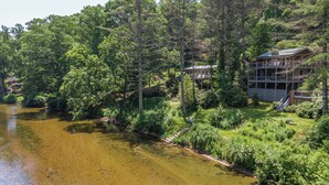 A lakeside property with a multi-level house surrounded by dense forest. - Knotty Pine (West Jefferson)