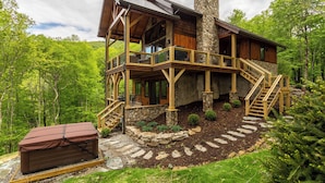 A log cabin with a stone chimney, wooden deck, and a stone staircase leading to the upper level. - Blue Ridge View at Eagles Nest (Banner Elk)