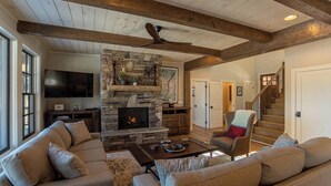 A spacious living room with a stone fireplace, a large sofa set, and a wooden ceiling. - Lakeshore Retreat at Sweetgrass (Blowing Rock)