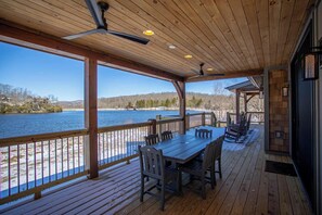 A wooden deck with a table and chairs overlooking a lake. - Lakeshore Retreat at Sweetgrass (Blowing Rock)