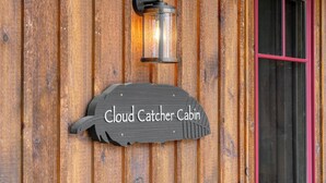 Una cabaña de madera con un letrero que dice "Cloud Catcher Cabin" y un farol encima.