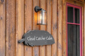 A wooden cabin with a sign reading "Cloud Catcher Cabin" and a lantern above it. - Cloud Catcher at Eagles Nest (Banner Elk)