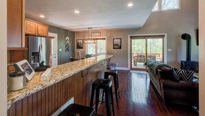 Une cuisine moderne dotée d’un plan de travail en granit, de meubles en bois et d’un réfrigérateur en acier inoxydable.
