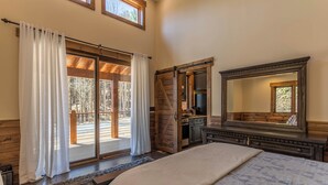 A bedroom with a large bed, a dresser, a mirror, and a sliding glass door leading to a deck. - Hook Wine and Sinker at Eagles Nest (Banner Elk)