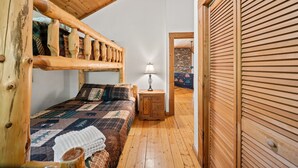 A cozy room with a wooden bunk bed, a small bedside table with a lamp, and a quilted bedspread. - Mountain Masterpeace (Banner Elk)
