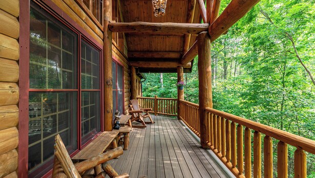 Eine Holzterrasse mit Geländer, Holzbanken und einer hängenden Laterne.