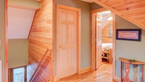 Un intérieur en bois avec un plafond incliné, une porte en bois et une enseigne encadrée accrochée au mur.