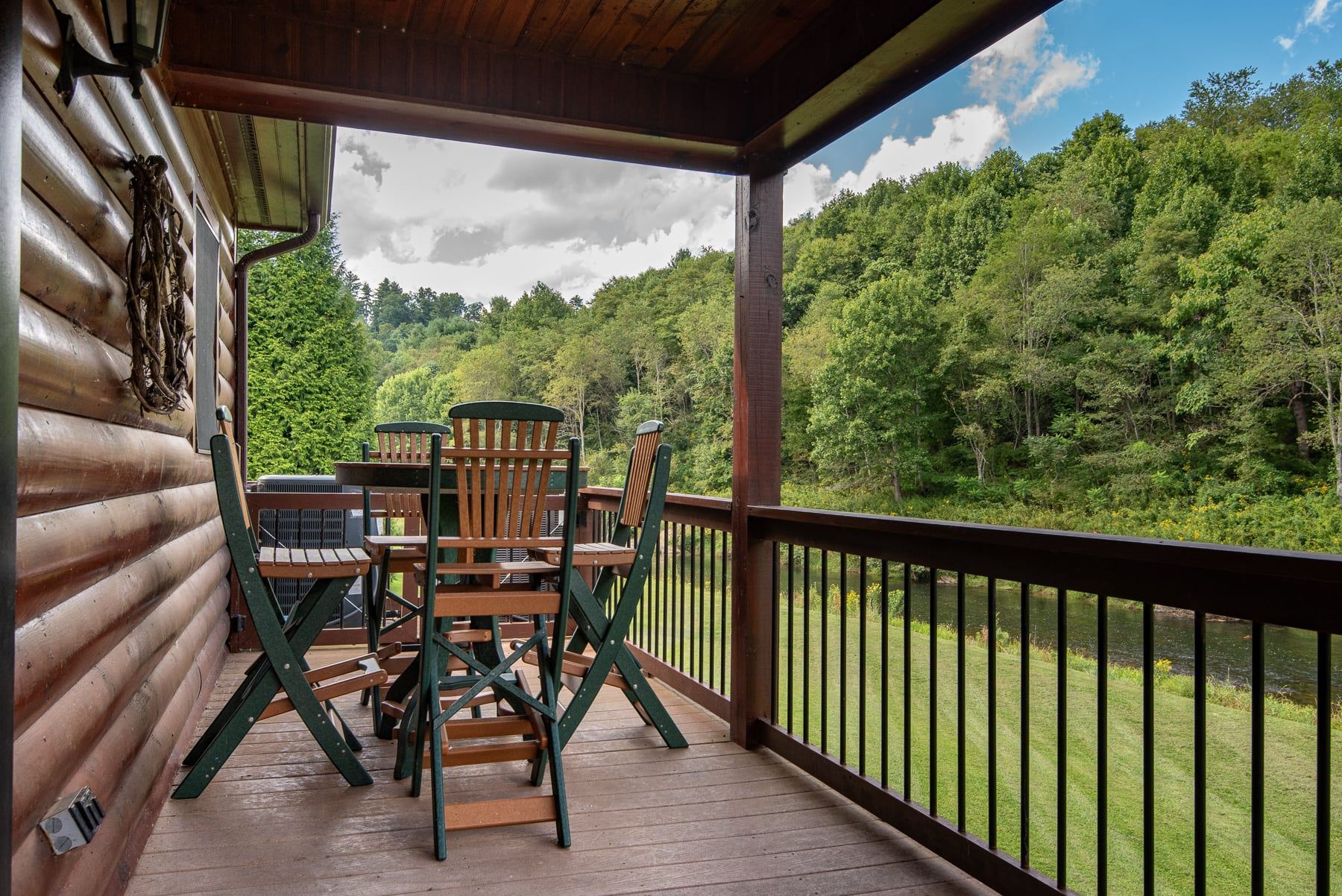 A wooden deck with a table and chairs, overlooking a forested area.