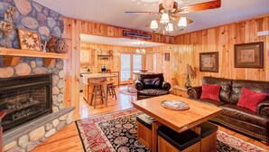 L’intérieur d’une cabane est agrémenté d’une cheminée en pierre, de murs en bois, d’un coin repas et d’un canapé en cuir.