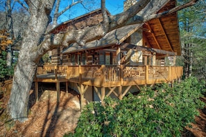 A wooden cabin with a balcony, surrounded by trees. - Fox's Lair (Sugar Grove)