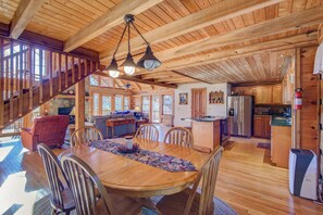 A spacious wooden cabin with a dining area, kitchen, and a staircase leading to a loft. - Fox's Lair (Sugar Grove)