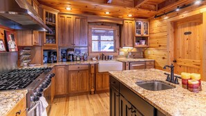 Cocina tipo cabaña de madera con estufa a gas, encimeras de granito y armarios de madera.
