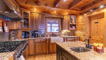 A wooden cabin-style kitchen with a gas stove, granite countertops, and wooden cabinets.
