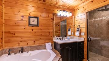 A wooden cabin bathroom with a large bathtub, a shower, and a vanity with a mirror.