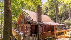 A cabin with a stone chimney, wooden deck, and a covered porch. - Bucks Cabin (Boone)