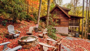 A cabin with a stone fire pit, wooden chairs, and a wooden deck. - Bucks Cabin (Boone)