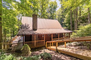 Une cabane dotée d’une terrasse en bois, d’une cheminée et d’un porche abrité.