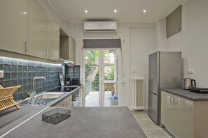 A modern kitchen with a grey countertop, stainless steel appliances, and a view to a patio area. - Like Home in Kalithea (Kallithea)