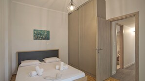 Un dormitorio con cama, un cuadro en la pared, un armario y una puerta que da a otra habitación.