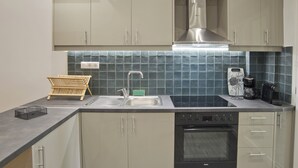 Una cocina moderna con extractor de acero inoxidable, horno empotrado y un lavabo con escurreplatos.