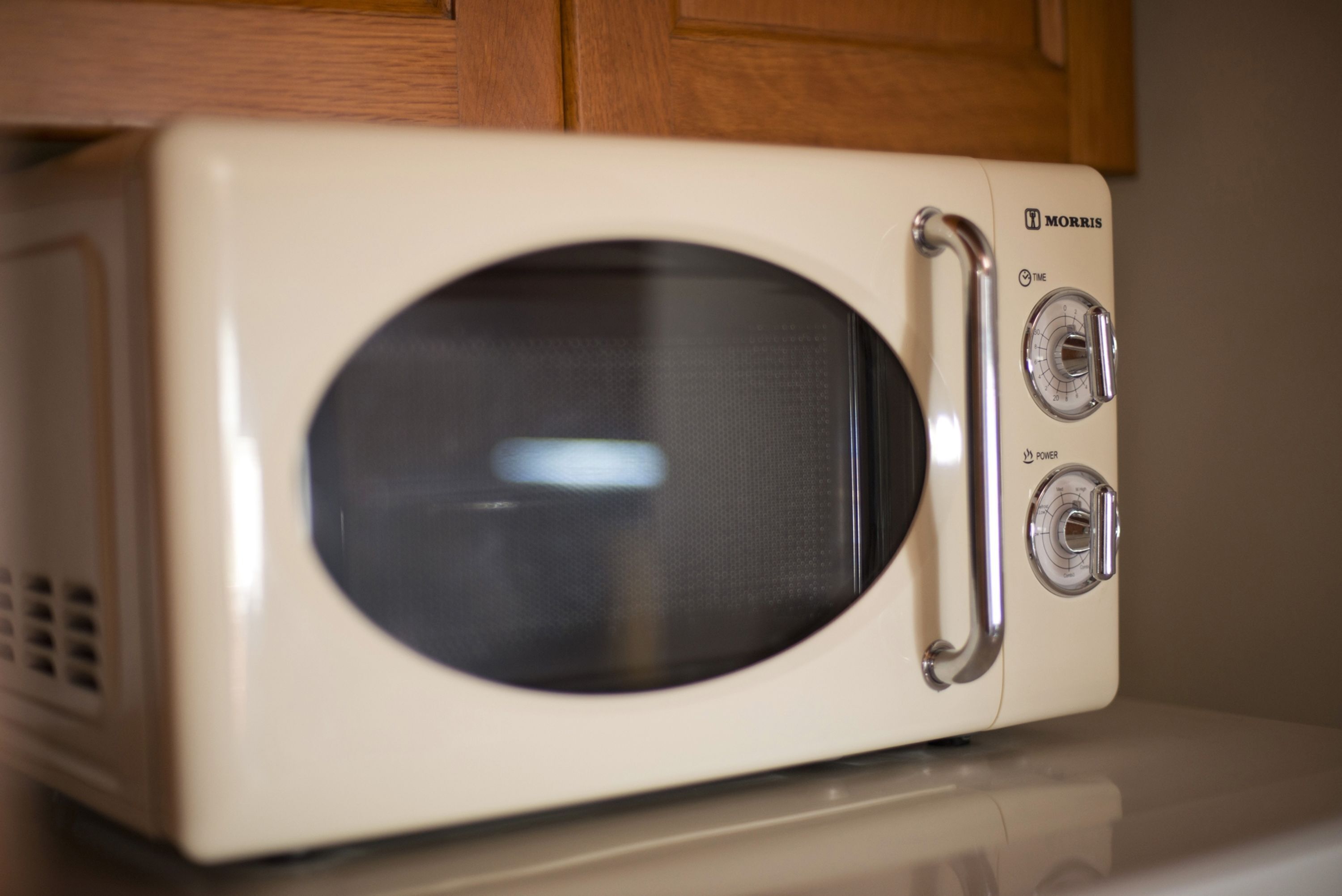 A white microwave with two dials and a vent on the left side.
