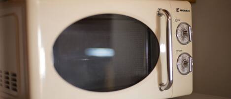 A white microwave with two dials and a vent on the left side.