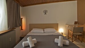 A neatly made bed with two pillows, a wooden headboard, a nightstand with a lamp, and a small table with a chair. - Apos Place in Pefki With 1 Bedrooms and 1 Bathrooms (Lykovrysi-Pefki)