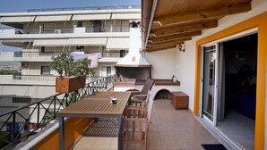 A balcony with a wooden table and chairs, a potted plant, and a barbecue grill. - Apos Place in Pefki With 1 Bedrooms and 1 Bathrooms (Lykovrysi-Pefki)
