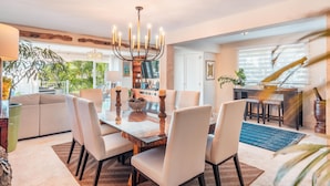 A spacious living area with a dining table, chairs, a chandelier, and a view of the outdoors. - Tenis Villa 18 in Casa De Campo (La Romana)